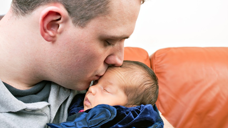 En far pussar sin bebis på pannan